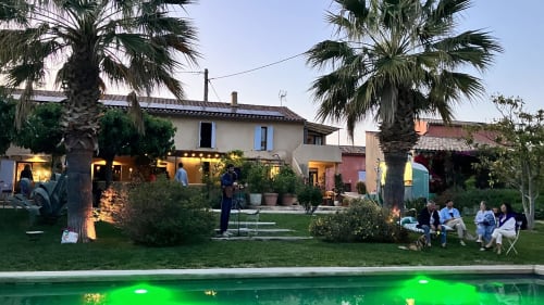 Guesthouse Clos Bb à Saint-Cyr sur Mer avec terrasse illuminée, piscine, palmiers et clients détendus au crépuscule