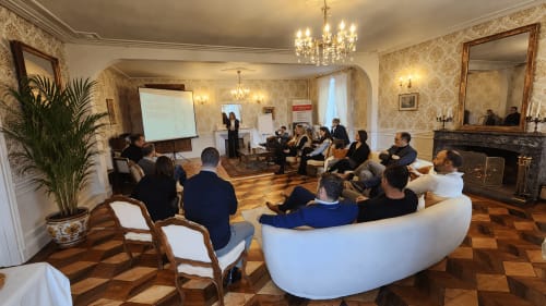Élégante salle de réunion du Château de la Rochetière à Marcilloles avec cheminée, lustre et participants en tenue professionnelle