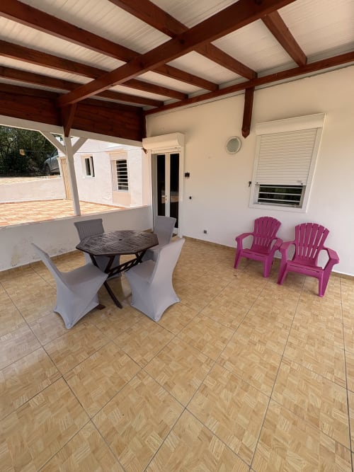 Terrasse couverte avec table à manger et chaises magenta à la villa La Maison Ihy à Grand-Bourg, Guadeloupe