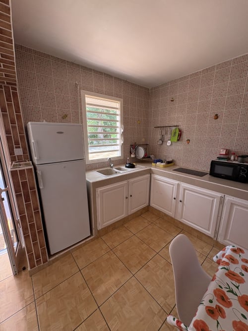 Cuisine contemporaine de la villa La Maison Ihy à L'ASETA PARADISE, Grand-Bourg avec mobilier blanc, réfrigérateur et vue sur mer