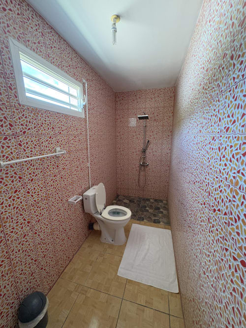 Salle de bain moderne de la villa L'Aseta Paradise avec carrelage en mosaïque rouge, toilettes blanches, douche et puits de lumière