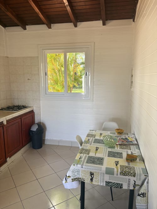 Coin repas de la villa La Maison Hator à L'ASETA PARADISE, Grand-Bourg avec table à manger, cuisinière à gaz et vue sur le jardin