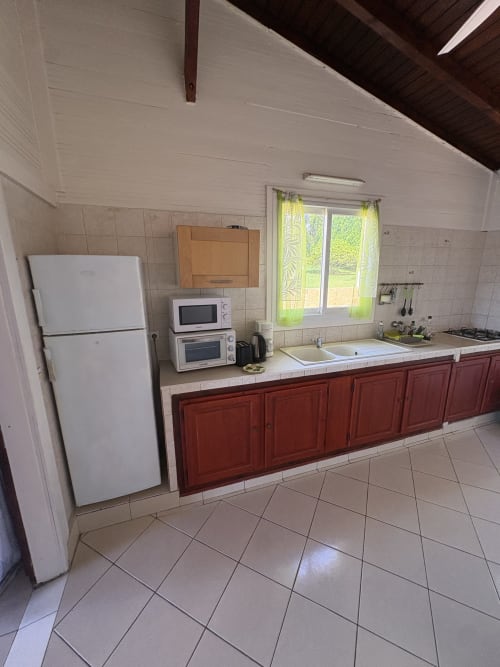Cuisine spacieuse de la villa La Maison Hator à L'Aseta Paradise, Grand-Bourg, avec mobilier rouge, électroménagers blancs et jardin