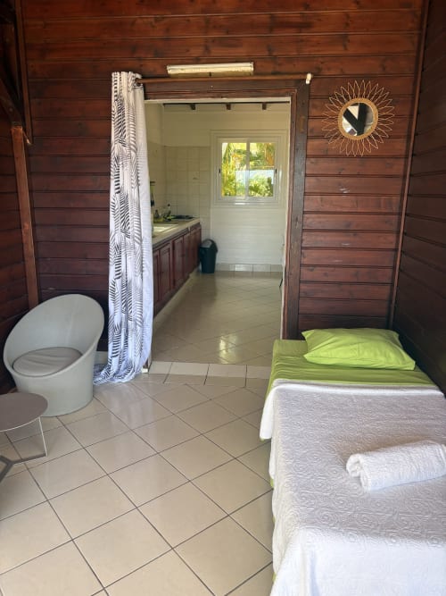 Spacieuse chambre de villa à Grand-Bourg avec lit, salle de bain attenante, carrelage et murs en bois