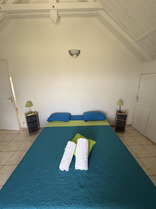 Chambre spacieuse de la villa La Maison Mâat avec lit queen-size, oreillers bleus, literie verte et tables de nuit avec lampes chez L'ASETA