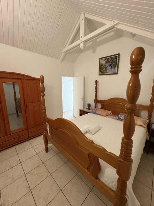 Lit baldaquin en bois dans chambre lumineuse avec plafond voûté, garde-robe et vue mer à L'Aseta Paradise, Grand-Bourg