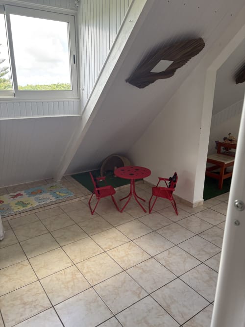 Aire de jeux pour enfants à la villa La Maison Mâat, Grand-Bourg avec table et chaises rouges sur sol carrelé