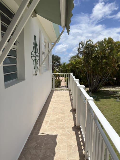 Terrasse ensoleillée de la villa L'ASETA PARADISE à Grand-Bourg avec palmiers, vue sur jardin et espace détente couvert