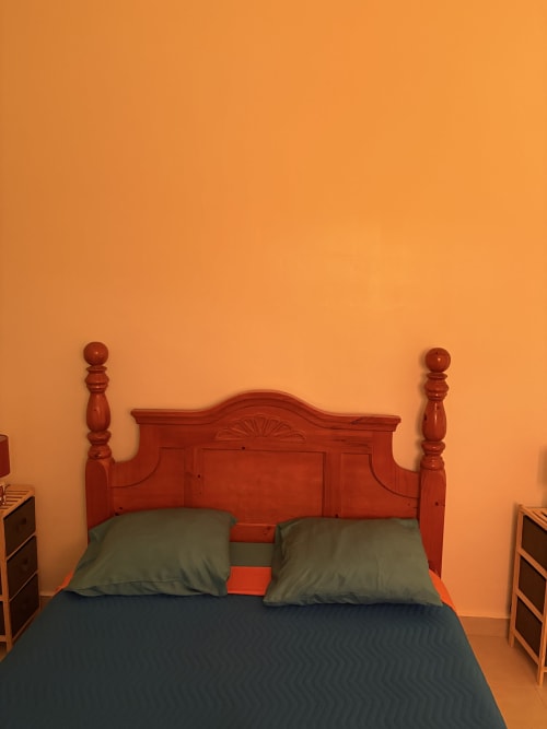 Lit en bois rouge avec coussins verts dans la chambre orange vif de la villa L'Aseta Paradise, Grand-Bourg Guadeloupe