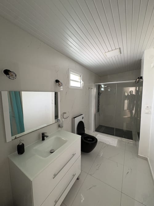 Salle de bain moderne de la villa L'ASETA PARADISE avec sols en marbre blanc, vasque, toilettes noires et douche à l'italienne vitrée