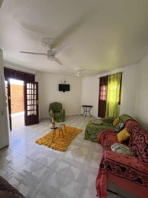 Spacieux séjour de la villa L'ASETA PARADISE à Grand Bourg avec sièges confortables, TV écran plat, ventilateurs