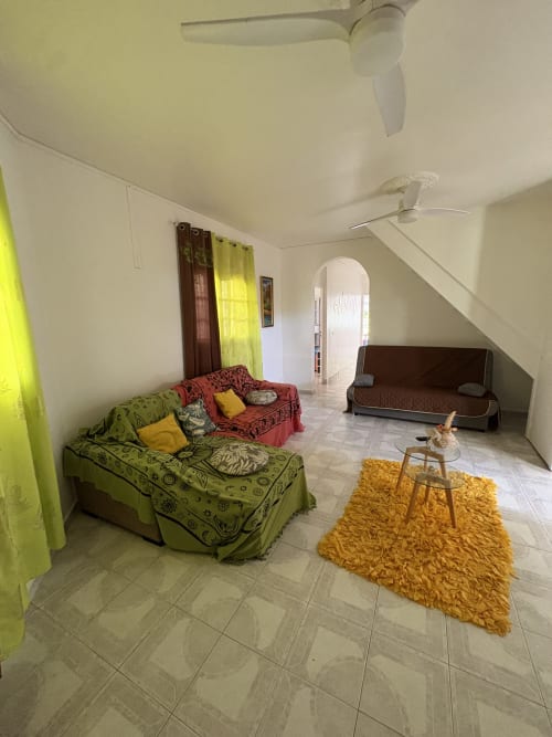 Lumineux salon de villa avec lit vert, canapé rouge, tapis jaune et carrelage à L'ASETA PARADISE, Grand Bourg