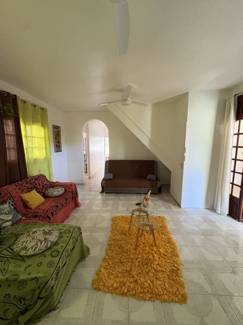 Salon spacieux de la villa Maison Aseta2 à Grand Bourg, avec canapés colorés, tapis jaune et accès à la vue sur jardin