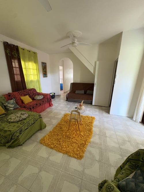 Spacieux séjour de la villa Maison Aseta2 à Grand Bourg avec ameublement coloré, carrelage et vue sur le jardin