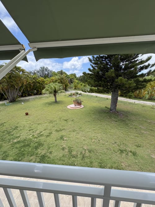 Vue spacieuse du jardin depuis la terrasse de la villa Maison Aseta2 à L'ASETA PARADISE, avec pelouse luxuriante, palmiers et tropical