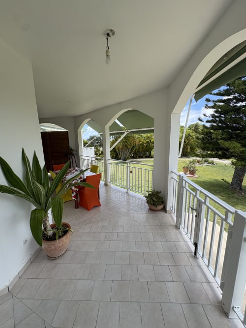 Terrasse couverte spacieuse de la villa L'Aseta Paradise à Grand Bourg avec vue sur jardin, plantes en pots et mobilier confortable