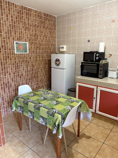 Cuisine colorée de la villa L'ASETA PARADISE à Grand-Bourg avec murs de briques, nappe verte et appareils rétro