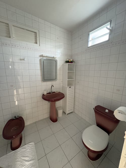 Salle de bain de la villa La Maison Aseta à L'ASETA PARADISE, Grand-Bourg avec fixtures bordeaux, lavabo sur piédestal et carrelage blanc