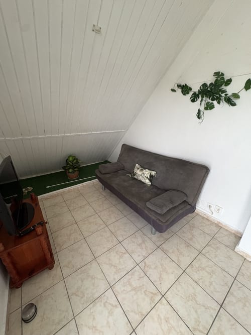 Studio minimaliste en grenier avec canapé gris, plantes en pot et carrelage à la villa La Maison Mâat, Grand-Bourg, Guadeloupe