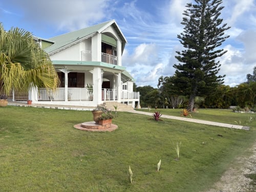 Villa La Maison Mâat à L'ASETA PARADISE, Grand-Bourg, Guadeloupe : élégante demeure coloniale blanche aux toits verts, jardin impeccable