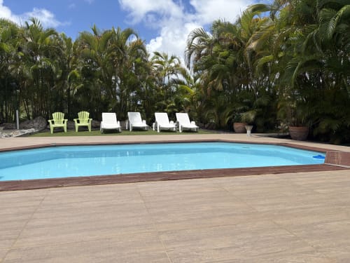Piscine de villégiature tropicale à L'ASETA PARADISE à Grand-Bourg, Guadeloupe, avec eau turquoise, chaises longues et palmiers.