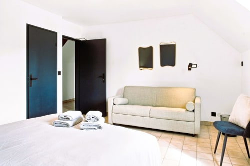 Chambre Premium Family de l'Hôtel le Tilleul à Corps : canapé beige, lit blanc, portes noires et vue sur les montagnes