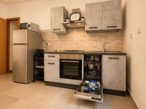 Cucina moderna negli Apartamenti Castelli, Albano Laziale, con elettrodomestici in acciaio inox, lavastoviglie e fornello a gas