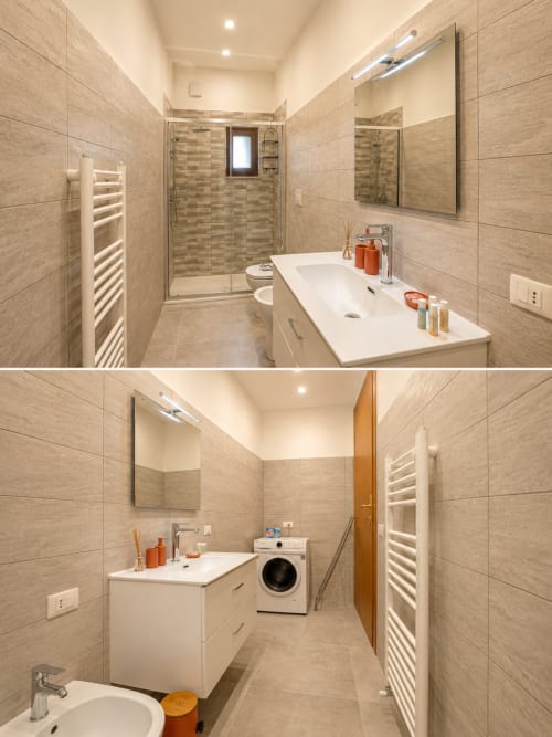 Bagno moderno di Castelli Apartments con piastrelle beige, lavabo bianco, specchio, doccia, WC e scaldasalviette