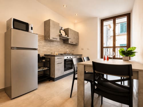 Cucina moderna e zona pranzo negli Appartamenti Castelli con elettrodomestici in acciaio inox, mobili beige e vista città dal balcone