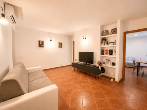 Soggiorno moderno negli Appartamenti Castelli con divano beige, TV a schermo piatto, pavimenti in cotto e mensole bianche ad Albano