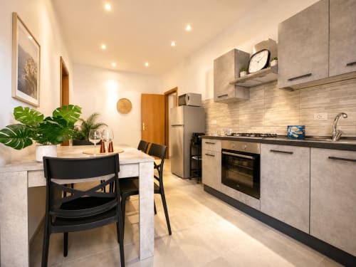 Cucina e zona pranzo moderna negli Appartamenti Castelli, Albano Laziale, con elettrodomestici in acciaio inossidabile e sedie nere