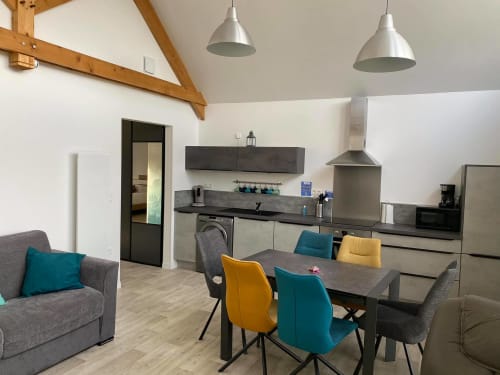 Cuisine ouverte et salle à manger du gîte Belle Vue d'Olhain avec chaises colorées et acier inoxydable