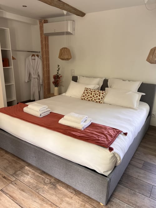 Chambre confortable à La Maison de Vaison avec lit queen-size, draps blancs et poutres en bois rustique