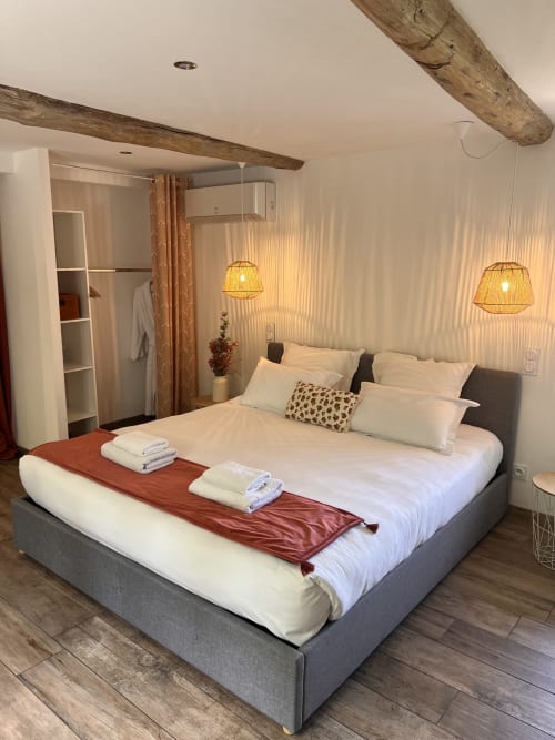 Chambre moderne à La Maison de Vaison avec lit queen-size, suspensions, poutres apparentes et décoration contemporaine