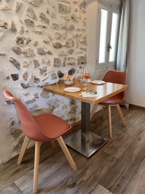 Ambiance intimiste à La Maison de Vaison à Vaison-la-Romaine : table en bois, chaises en terre cuite et mur de pierre rustique