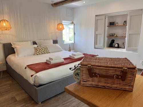 Chambre lumineuse à La Maison de Vaison B&B avec lit queen-size, bagages en osier, suspensions et rangements intégrés