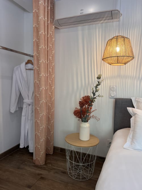 Chambre d'hôtel moderne à La Maison de Vaison avec luminaire suspendu, table en bois fleurie et rideaux pêche à motifs