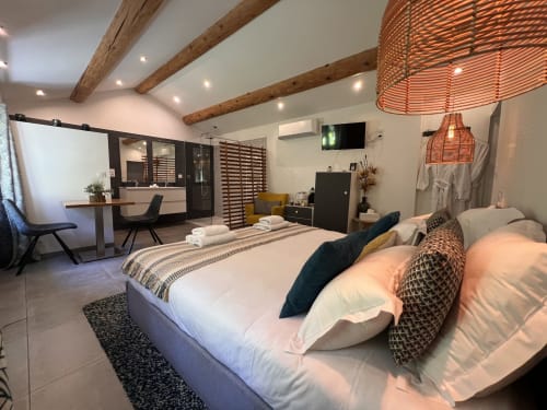 Chambre moderne à La Maison de Vaison, avec lit blanc, poutres en bois, espace de travail et salle de bain privée