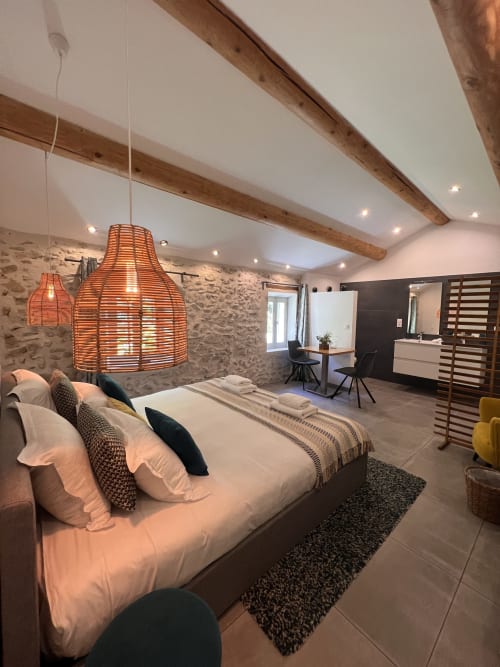 Chambre confort à La Maison de Vaison à Vaison-la-Romaine avec literie moderne, luminaires suspendus tissés, poutres apparentes et pierre