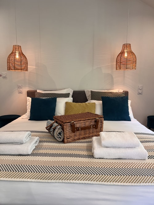 Chambre moderne à La Maison de Vaison avec suspensions tissées, coussins bleu-vert et équipements de bienvenue