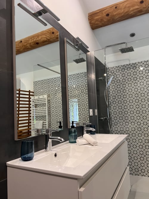 Salle de bain moderne à La Maison de Vaison avec vasque blanche, miroir, douche carrelée motifs et poutres en bois