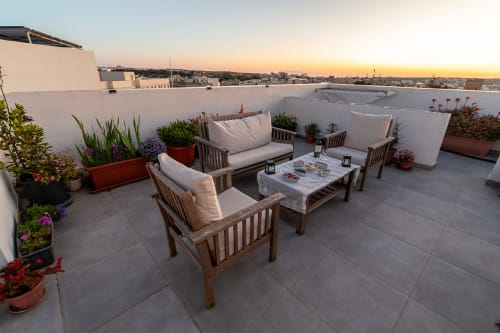 Rooftop terrace at Estrella Lodging in Rabat with wooden seating, potted flowers, and city sunset views