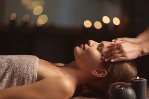 Femme recevant un massage de la tête à l'hôtel spa Eucalyptus Ethnic à El Ghazouane, Maroc, avec ambiance aux chandelles