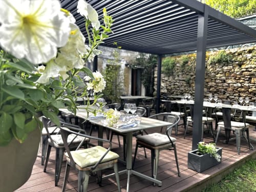 Outdoor dining patio at La Musardine En Vexin with white flowers, modern lounge seating, and stone walls in Omerville