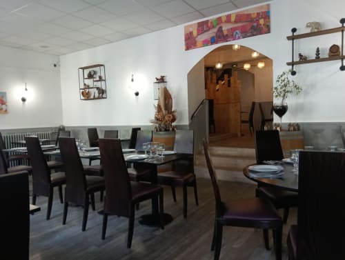 Modern dining room at La Musardine En Vexin hotel in Omerville with dark chairs, wooden tables, and ambient lighting