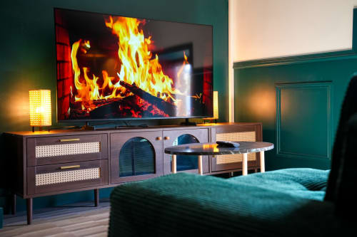 Chambre moderne aux Séjours Ardennais avec cheminée, TV, mobilier rétro, murs accent bleu-vert et décor élégant