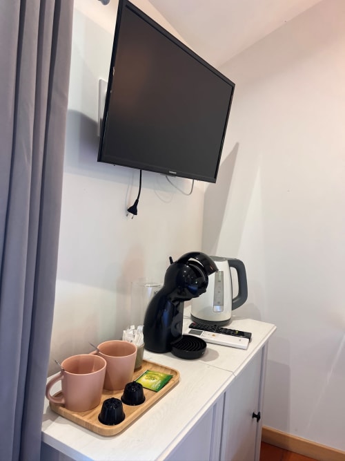 Station de café avec tasses roses et machine Nespresso dans la chambre de l'hôtel La Maison de Vaison, TV murale