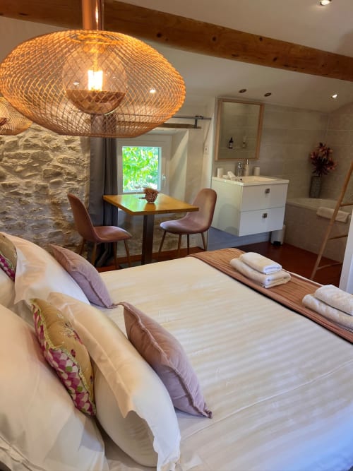 Chambre Standard spacieuse à La Maison de Vaison avec lit queen, luminaire pendant tissé, coin repas et salle de bain attenante