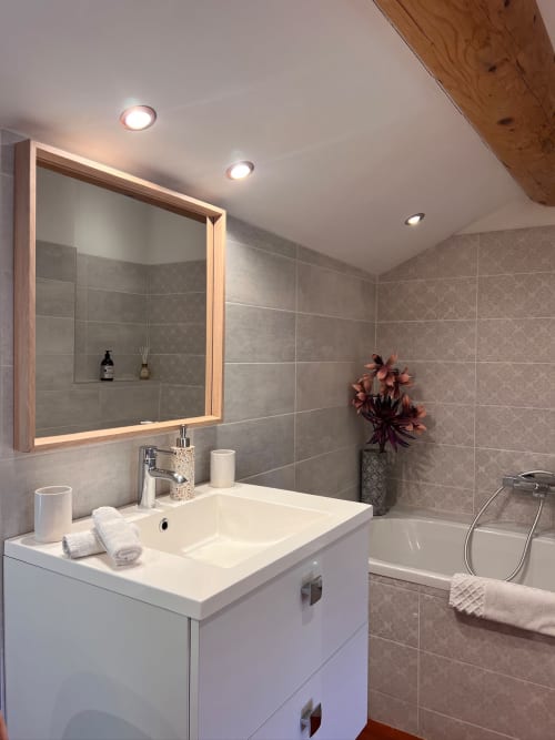 Salle de bain moderne à La Maison de Vaison B&B avec vasque blanche, miroir éclairant, murs en carrelage gris et baignoire