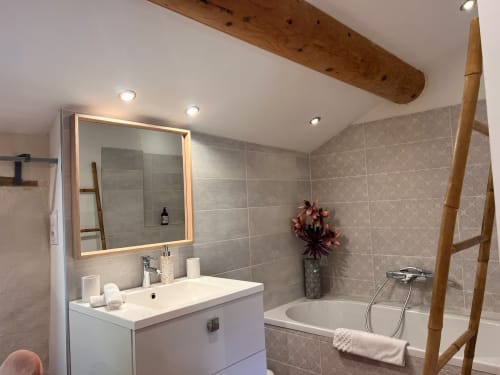 Salle de bain moderne à La Maison de Vaison avec miroir éclairé, lavabo blanc, baignoire et accents en bois